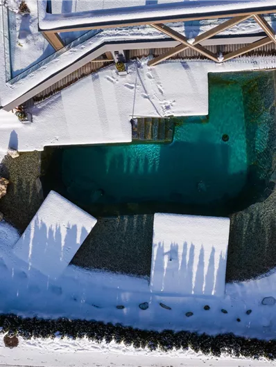 A beautiful swimming pool in a snow-covered garden. The architecture and the clear water surface create an inviting contrast to the wintry surroundings.