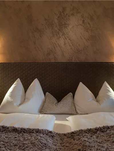Een gezellige slaapkamer met een groot bed en decoratieve kussens. De warme lichten creëren een ontspannen sfeer.