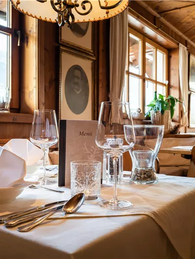 Ein gemütliches Restaurant mit Holzinterieur und großer Fensterfront. Der Tisch ist liebevoll gedeckt mit Besteck und Gläsern.