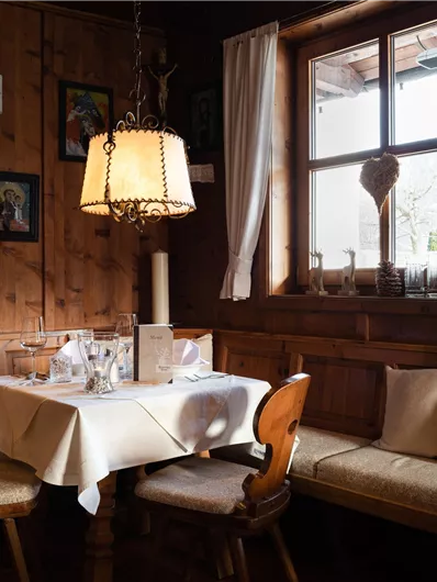 Ein gemütliches Restaurant mit Holzwänden und einem Tisch, der für Gäste gedeckt ist. Das Fenster bietet einen Blick nach draußen und die Einrichtung ist traditionell.