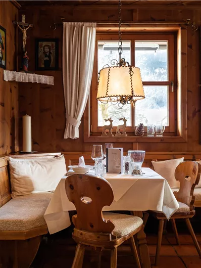 Ein gemütliches Restaurant mit Holzverkleidung und einer hellen Fensterfront. Die Einrichtung ist traditionell und einladend, mit Bildern an den Wänden.