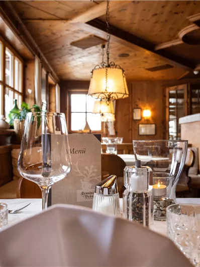 Ein gemütliches Restaurant mit Holzdekor und warmem Licht. Der Tisch ist schön gedeckt mit Gläsern und Servietten.