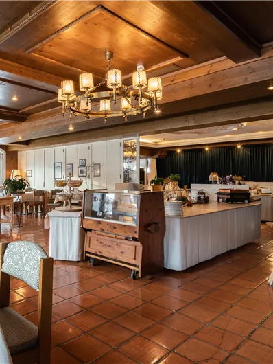 Ein elegantes Restaurant mit Holzvertäfelungen und warmem Licht. Die Tische sind schön gedeckt und ein Buffet ist sichtbar.