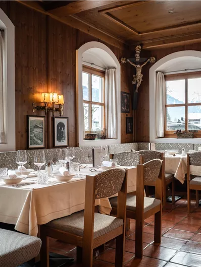 Ein gemütliches Restaurant mit Holzdekor und mehreren Tischen. Die Fenster bieten Blick auf eine winterliche Landschaft.