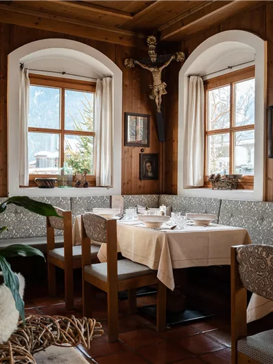 Ein gemütliches Restaurant mit Holzvertäfelung und dekorativen Fenstern. Die Tische sind elegant gedeckt und es gibt Pflanzen für eine angenehme Atmosphäre.