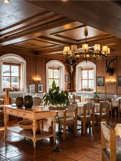 Ein gemütliches Restaurant mit Holzelementen und eleganter Beleuchtung. Die Tische sind schön gedeckt und große Fenster lassen viel Licht herein.