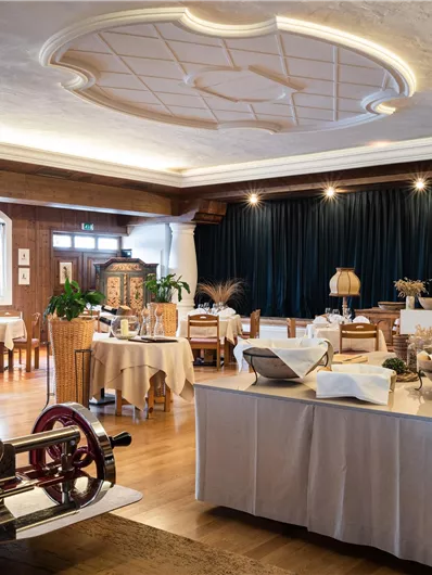 Ein stilvolles Restaurant mit eleganten Tischen und einer gemütlichen Atmosphäre. Im Vordergrund befindet sich eine alte Maschine, die einen historischen Charme verleiht.