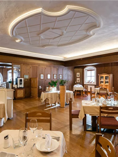 Ein elegantes Restaurant mit Holzwänden und stilvollen Tischen. Der Raum ist hell erleuchtet und schafft eine angenehme Atmosphäre.
