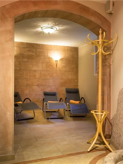 Een ontspannend wellnessgebied met ligbedden en een douche. De warme kleuren en de zachte verlichting creëren een rustgevende sfeer.