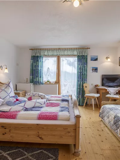 A cozy room with two beds and a seating area. Large windows provide plenty of daylight and a pleasant atmosphere.