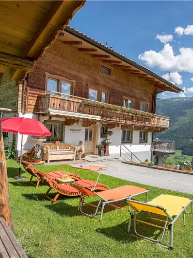 A beautiful wooden house on a meadow with a view of the mountains. Loungers and a swing invite you to relax.