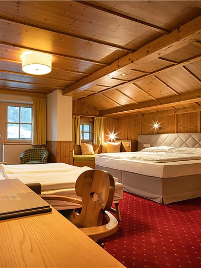 Ein gemütliches Schlafzimmer mit Holzelementen und einem großen Bett. Der Raum ist hell und einladend, mit einem Schreibtisch und einem Fernseher.