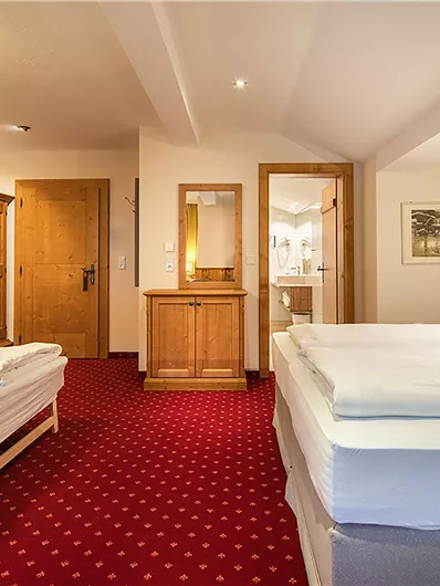 Ein komfortables Zimmer mit zwei Betten und einem modernen Baddesign. Der Raum ist hell und freundlich eingerichtet, mit Holzdetails und einem gemütlichen Ambiente.