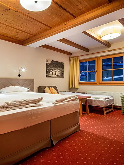 Ein gemütliches Hotelzimmer mit einem großen Bett und einem Holzdecke. Das Zimmer ist hell mit Fenstern, die einen Blick nach draußen bieten.