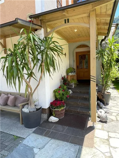 An inviting entrance area with plants and colorful flowers. The path leads to the front door under a bright porch.