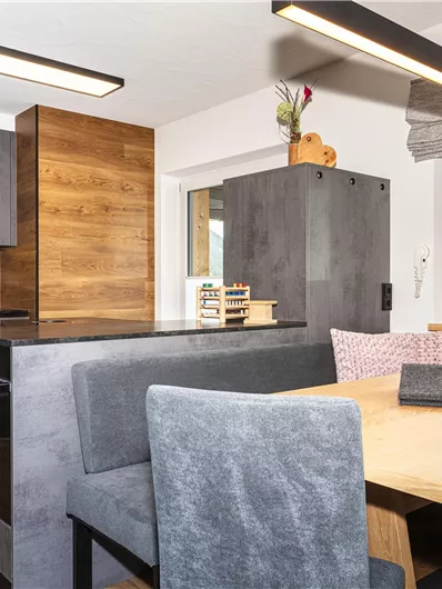 Een moderne keuken met houten en grijze elementen. Een eetgedeelte met een tafel en stoelen completeert de vriendelijke sfeer.