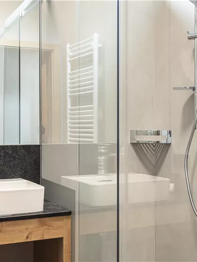 Een moderne badkamer met een douche en een wastafel. De glazen wanden en de strakke lijnen zorgen voor een elegante uitstraling.