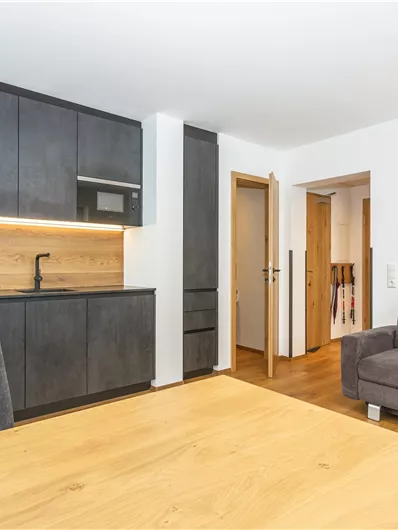 Een moderne keuken met een eetruimte en een gezellige bank. De muren zijn licht, en de ruimte lijkt uitnodigend en goed verlicht.