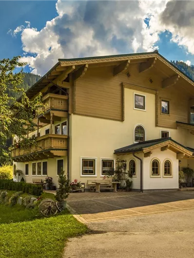 Een gezellig landhuis omgeven door weelderig groen en bergen op de achtergrond. De wolken geven de lucht een schilderachtige aanraking.