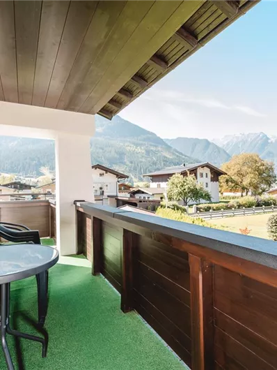 A beautiful balcony with a view of the mountains. The room is furnished with a table and chairs.