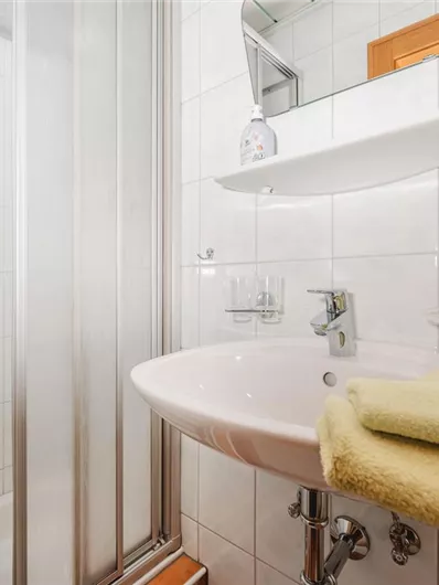 A modern bathroom with a shower and a sink. Yellow towels are ready.