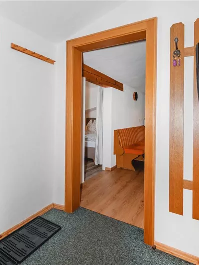 An inviting hallway with wood paneling and a mirror wall. In the background, a cozy living area can be seen.