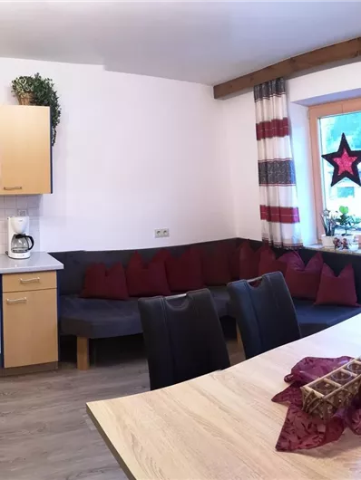 A modernly furnished kitchen with a dining area and a cozy seating area. Large windows provide plenty of light and an inviting atmosphere.