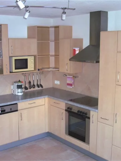 A modern kitchen with wooden cabinets and stainless steel appliances. It features a stove, a refrigerator, and ample storage space.