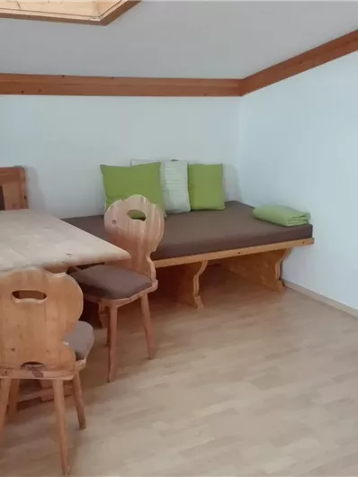 Een gezellige kamer met houten meubels, een eettafel en een zithoek. Aan de muur staat een televisie.