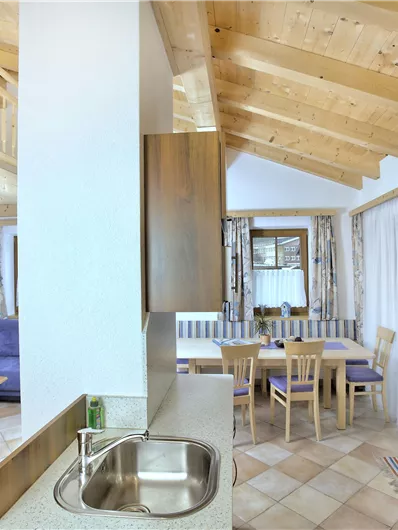 Een modern appartement met een open keuken en een eetruimte. Helle meubels en grote ramen zorgen voor een uitnodigende sfeer.