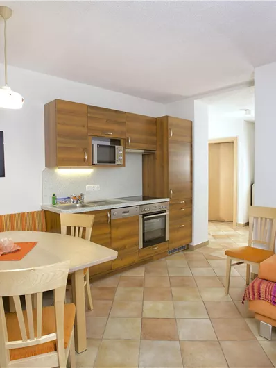 Een heldere en moderne keuken met een eettafel en comfortabele zitplaatsen. Het houten meubilair en de open ruimtes creëren een uitnodigende sfeer.