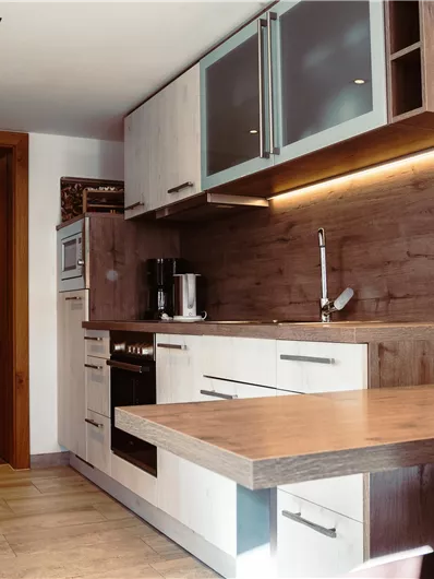 A modern kitchen with wooden and white cabinets. The space is well-lit and friendly designed.