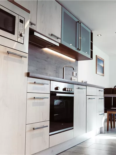 A modern kitchen with light wood cabinets and stainless steel appliances. A dining table with chairs is visible in the background.