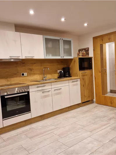 A modern kitchen with bright cabinets and wooden details. It is well-equipped and designed to be cozy.