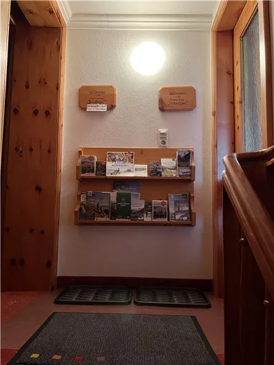An inviting hallway with wooden panels and warm lighting. On the wall, there is an information stand with brochures.