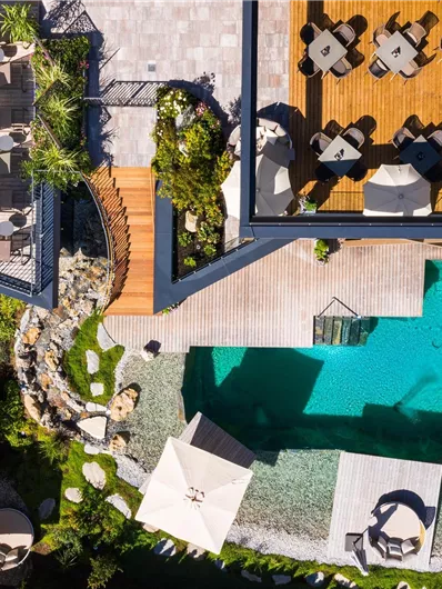 Ein elegantes Hotel mit einem klaren Pool und Liegen im Freien. Die Umgebung ist grün und einladend, ideal zum Entspannen.