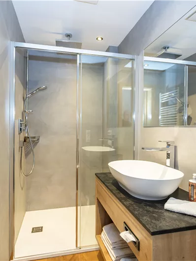 Een moderne badkamer met een glazen douche en een elegant wastafel. De muren zijn licht en de inrichting is stijlvol.