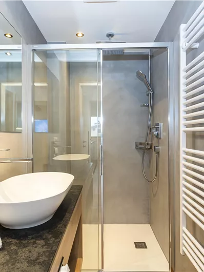 Een moderne badkamer met een douche en een stijlvol wastafel. De muren zijn in neutrale kleuren gehouden en er is een handdoekverwarming.
