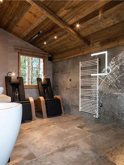 Ein modernes Badezimmer mit Holzdach und Betonfußboden. Es verfügt über elegante Armaturen und große Fenster, die viel Licht hereinlassen.