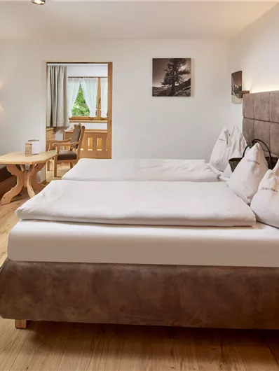 Ein modernes Hotelzimmer mit zwei Betten und einer gemütlichen Sitzecke. Das Zimmer hat große Fenster, die viel Licht hereinlassen.