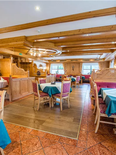 Ein gemütliches Restaurant mit Holzmöbeln und bunten Tischen. Die Einrichtung ist rustikal und einladend, ideal für ein entspanntes Essen.