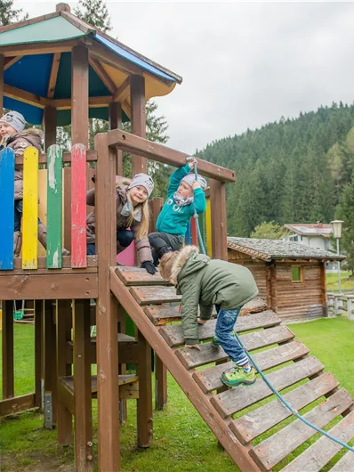 Ein Spielplatz mit bunten Rutschen und einem Klettergerüst. Kinder spielen und haben Spaß in einer grünen Landschaft.
