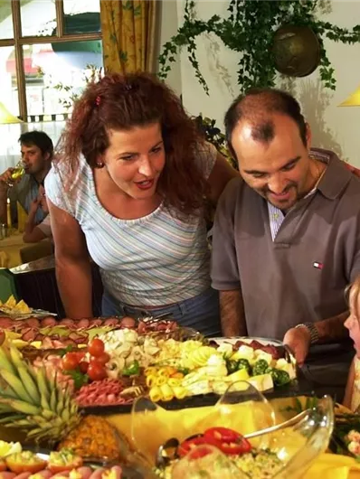 Een restaurant met een gevarieerde selectie van gerechten. Een gezin kijkt naar het eten en heeft samen plezier.