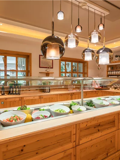 Ein einladendes Essensbuffet in einer modernen Küche. Die Holzregale und die warmen Lichter schaffen eine gemütliche Atmosphäre.