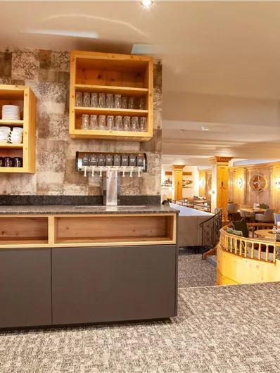 Ein moderner Empfangsbereich mit Holzregalen und einem eleganten Weinschrank. Der Raum ist hell und einladend gestaltet.