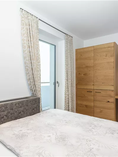 Een moderne slaapkamer met een groot bed en een flatscreen televisie. De ruimte heeft lichte muren en een gezellige houten kast.