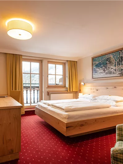 Ein modernes Hotelzimmer mit Holzdetails und einem großen Fenster. Die Einrichtung ist gemütlich und einladend, mit einem Bett und einem Sessel.