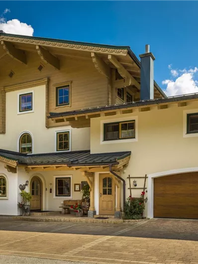 Een mooi, modern huis in alpine stijl met houtdetails. De gevel is licht en uitnodigend, omgeven door een pittoresk landschap.
