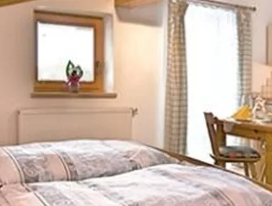 Een gezellige slaapkamer met een groot bed en decoratieve kussens. Op de achtergrond zijn een eetgedeelte en een badkamer zichtbaar.