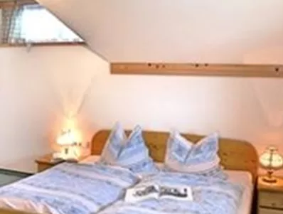 Een gezellige slaapkamer met een houten bed en zachte verlichting. De muren zijn licht en de ruimte heeft uitnodigende decoraties.